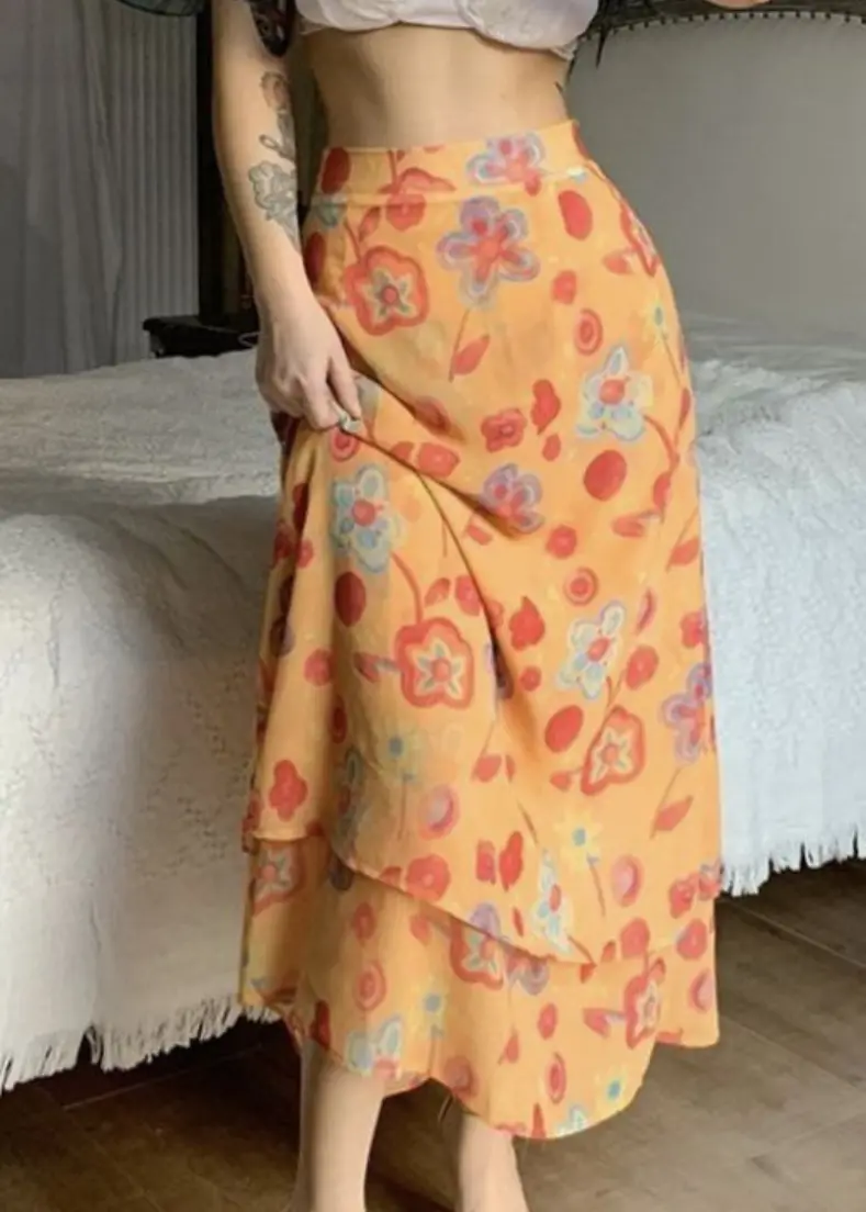A woman wearing a floral skirt and matching top, standing in a bright outdoor setting.  skirts for women in kerala
