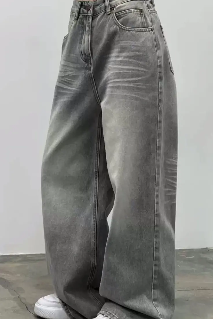 A woman stands confidently, wearing stylish jeans and a casual top, showcasing a modern fashion look.<br />
