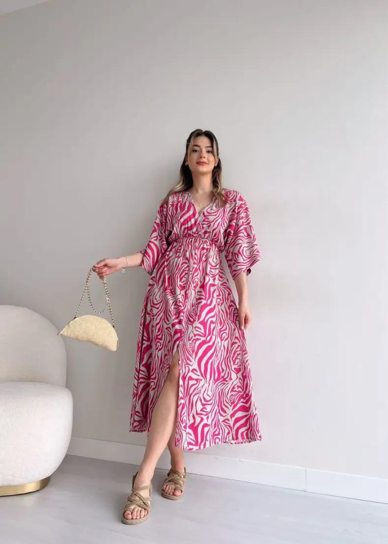  A woman wearing a pink dress sits gracefully on a white chair, exuA woman wearing a pink dress sits gracefully on a white chair, exuding elegance and style.ding elegance and style maxi dresses for women in kerala