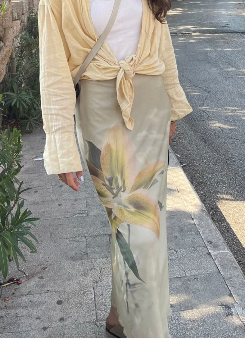 A woman dressed in a bright yellow shirt and matching yellow skirt stands confidently