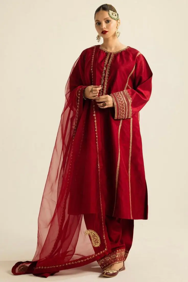 deep maroon kurta set with intricate golden embroidery on the neckline, sleeves, and dupatta, paired with matching pants and juttis party wear dresses for women in kerala