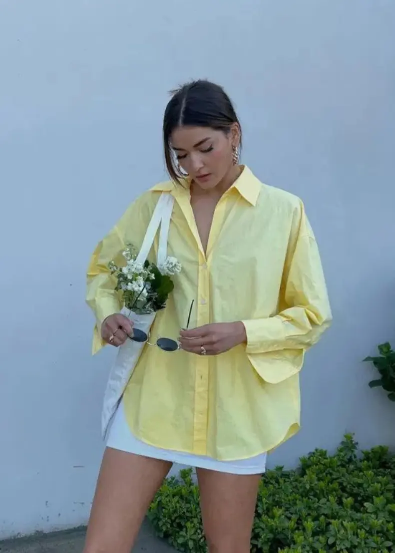 A woman dressed in a bright yellow shirt. exuding a cheerful demeanor. women's shirts in kerala